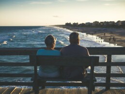 Retired couple on a boardwalk overlooking a beach