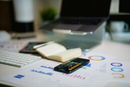 A desktop littered with sheets, charts, a calculator, and a ledger for debt consolidation evaluation