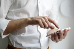 A man in a white shirt using a smart phone to automate his finances