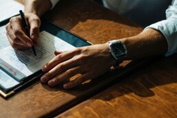 A close up image of a tax professional's hands as he takes notes on his client's financial responsibilities