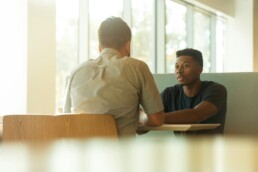 An agent sitting across a desk near a window, discussing life insurance coverage with a client