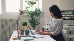 A young woman using a laptop at a desk to plan her tax deductions