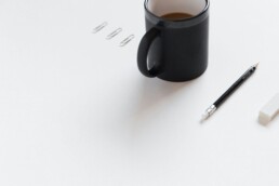 A simple white desktop designed with financial minimalism in mind. Atop is a few paperclips, a pencil, and a mug.