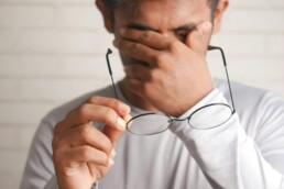 A frustrated man removing his glasses to relieve the tension in his forehead